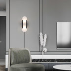Black Kristy sconce lit on a grey panelled wall above a green houndstooth chair