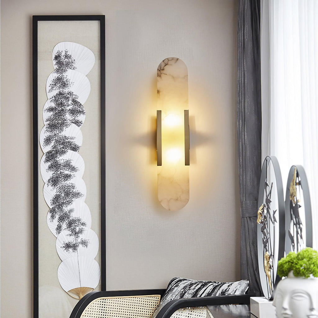Clérachic heavily veined alabaster Olraeia sconce on a linen wall beside framed fan artwork and a rattan chair