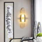 Clérachic heavily veined alabaster Olraeia sconce on a linen wall beside framed fan artwork and a rattan chair