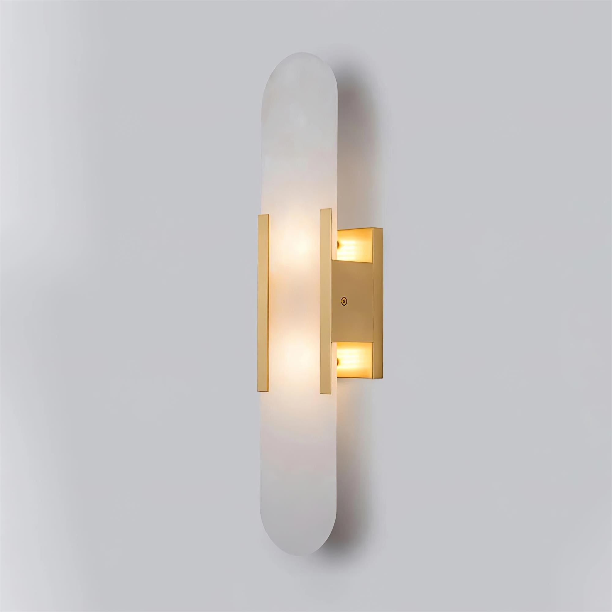 Clérachic slim brass Olraeia sconce angled right on grey, both bulb compartments lit inside the backplate