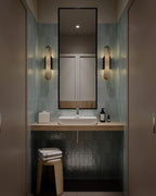 Two Clérachic Olraeia sconces with dark bars flanking a tall mirror over a basin in a green-tiled powder room