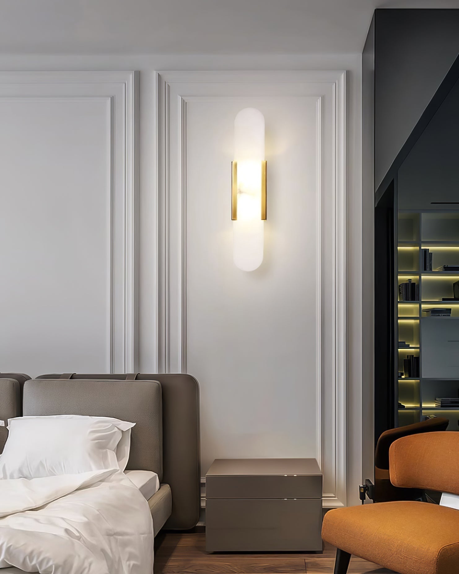 Clérachic olraeia sconce lit on a moulded bedroom panel above a taupe nightstand, bed linens in the foreground
