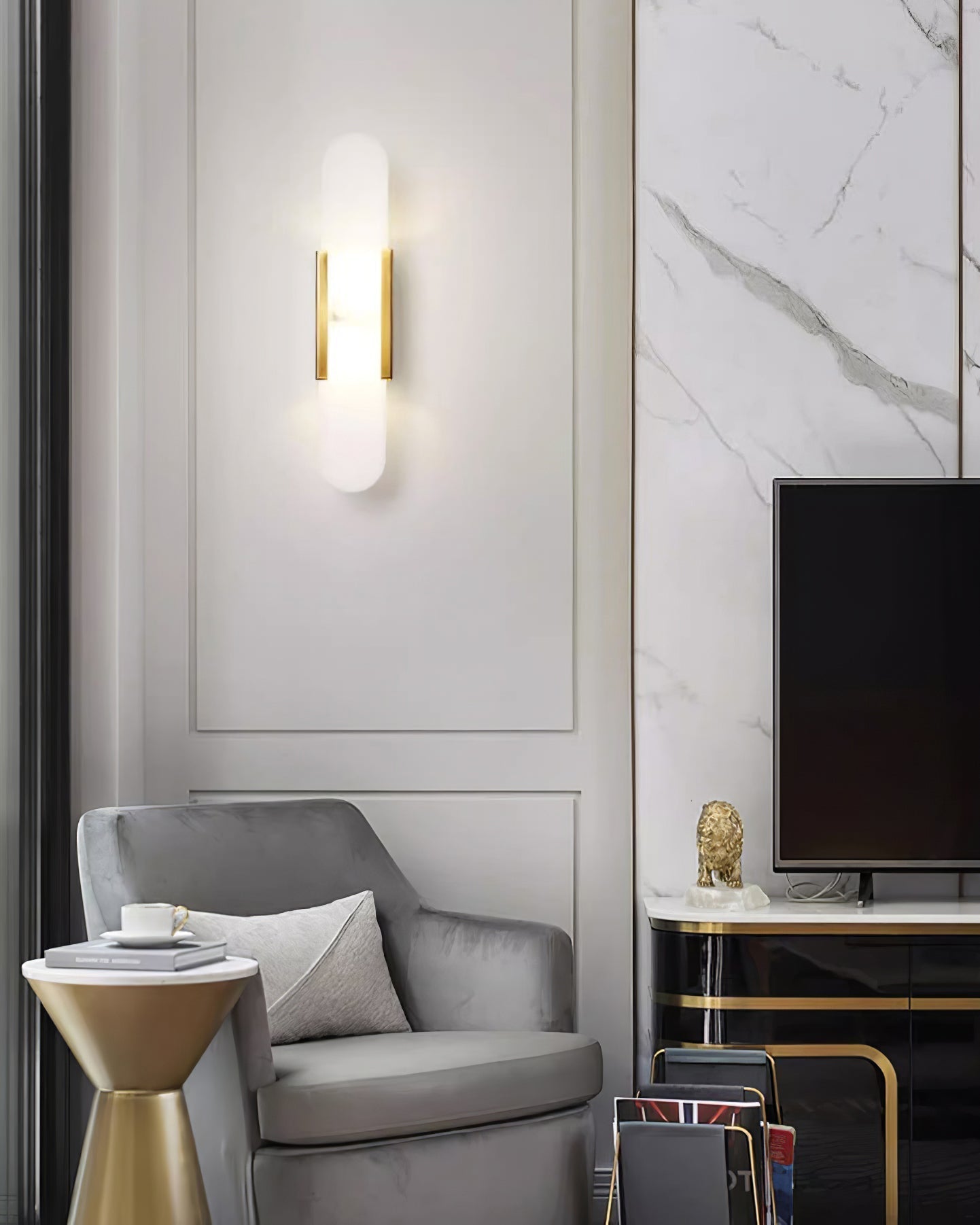 Clérachic brass Olraeia sconce on a panelled living-room wall next to a grey velvet armchair and marble surround