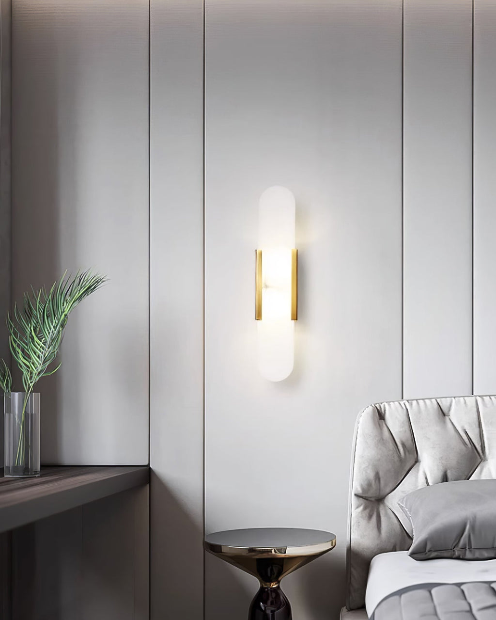 Clérachic brass Olraeia sconce on a grey panelled bedroom wall beside a tufted headboard and a gold side table