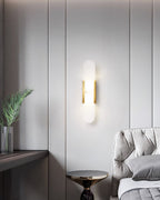 Clérachic brass Olraeia sconce on a grey panelled bedroom wall beside a tufted headboard and a gold side table