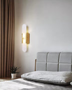 Clérachic brass Olraeia sconce beside heavy curtains in a bedroom, lighting the corner above a potted plant