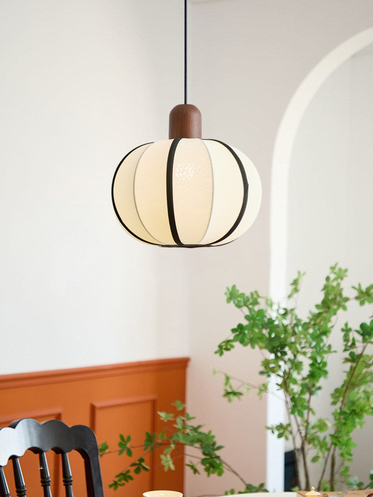 Under an archway near a potted plant, this Clérachic pendant's ribbed cream shade glows against orange wainscoting.