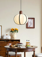 Above a round wood table set with sunflowers and drinks, this Clérachic pendant's cream shade glows warm.