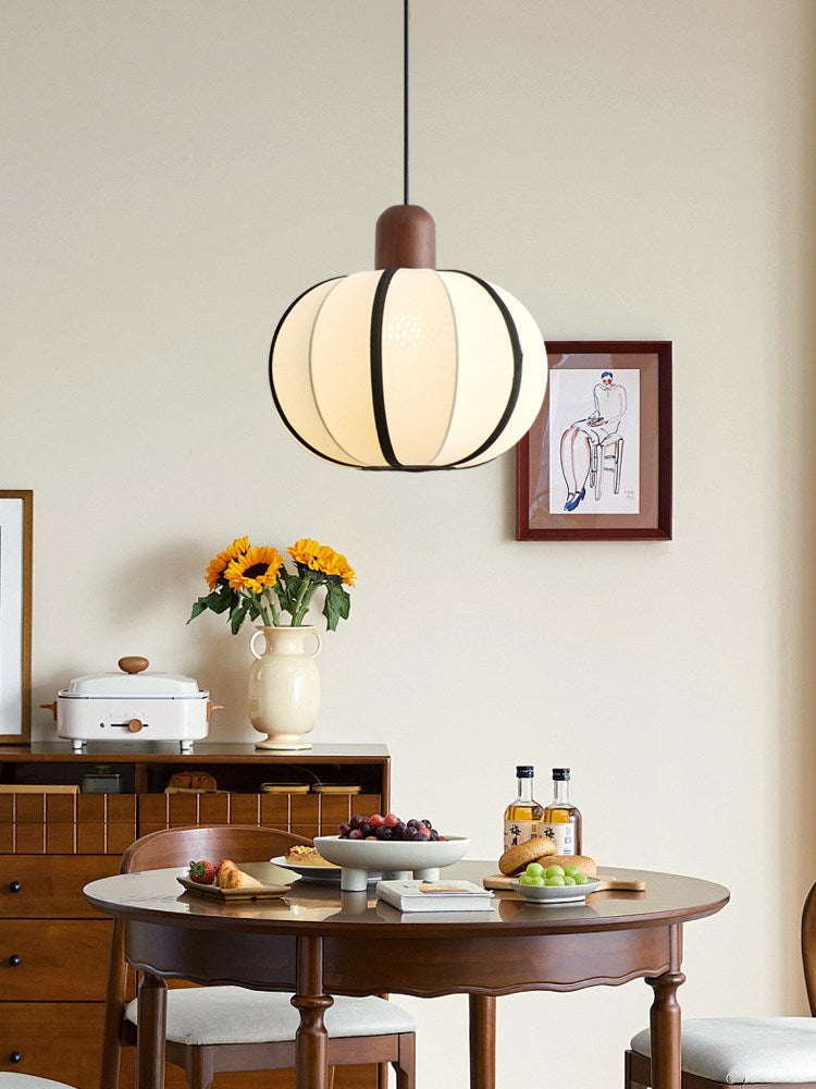 Above a round wood table set with sunflowers and drinks, this Clérachic pendant's cream shade glows warm.