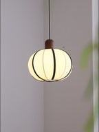 Close view of this Clérachic pendant's turned wood cap and black-seamed ribbed fabric shade, glowing softly.