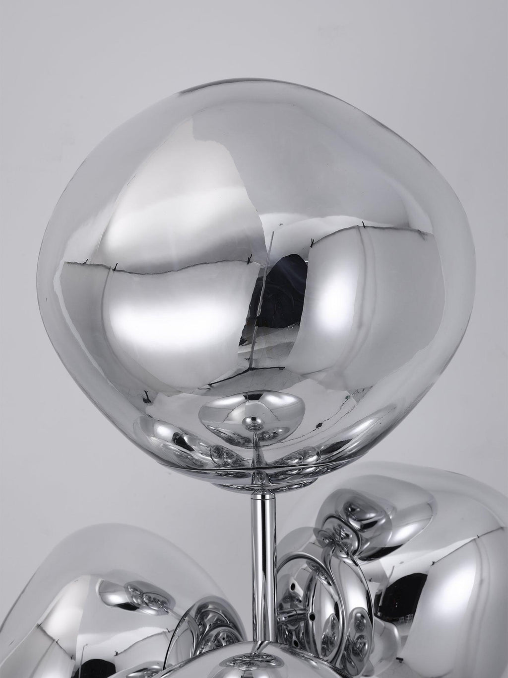 An extreme close-up of one mirror-chrome glass globe on this Clérachic floor lamp, its polished surface reflecting the studio around it.