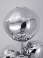 An extreme close-up of one mirror-chrome glass globe on this Clérachic floor lamp, its polished surface reflecting the studio around it.