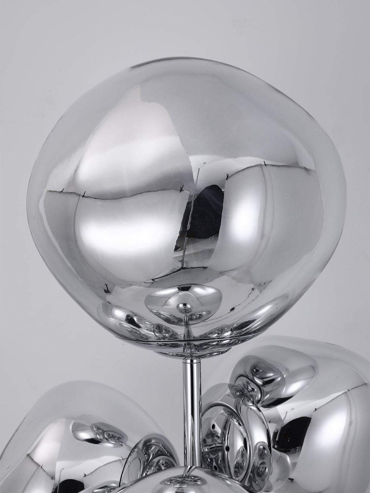 An extreme close-up of one mirror-chrome glass globe on this Clérachic floor lamp, its polished surface reflecting the studio around it.
