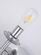Close-up of a clear filament bulb seated in the chrome socket of this Clérachic floor lamp, the mounting disc and rod visible behind it.