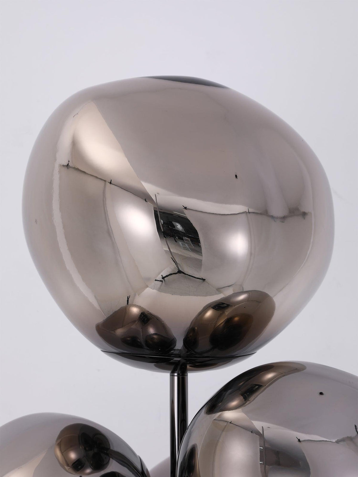 A macro view of clustered mirror-chrome globes on this Clérachic floor lamp, their polished surfaces showing faint reflected texture.