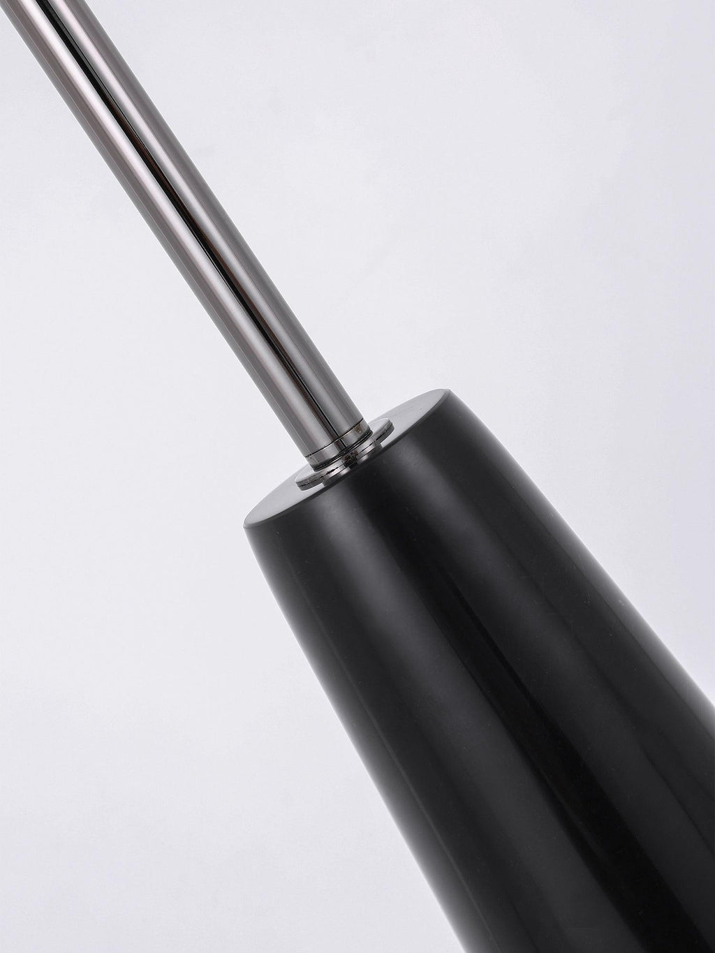 Close-up of the chrome rod meeting the glossy black conical base of this Clérachic floor lamp, the join shown against a plain backdrop.