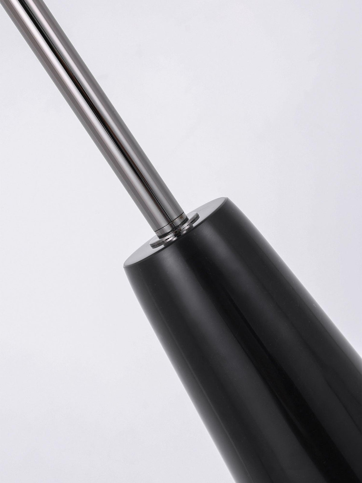 Close-up of the chrome rod meeting the glossy black conical base of this Clérachic floor lamp, the join shown against a plain backdrop.
