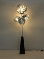 A moody, close-cropped view of this Clérachic floor lamp's smoke-glass globes glowing against a dark backdrop, filament bulbs visible inside.