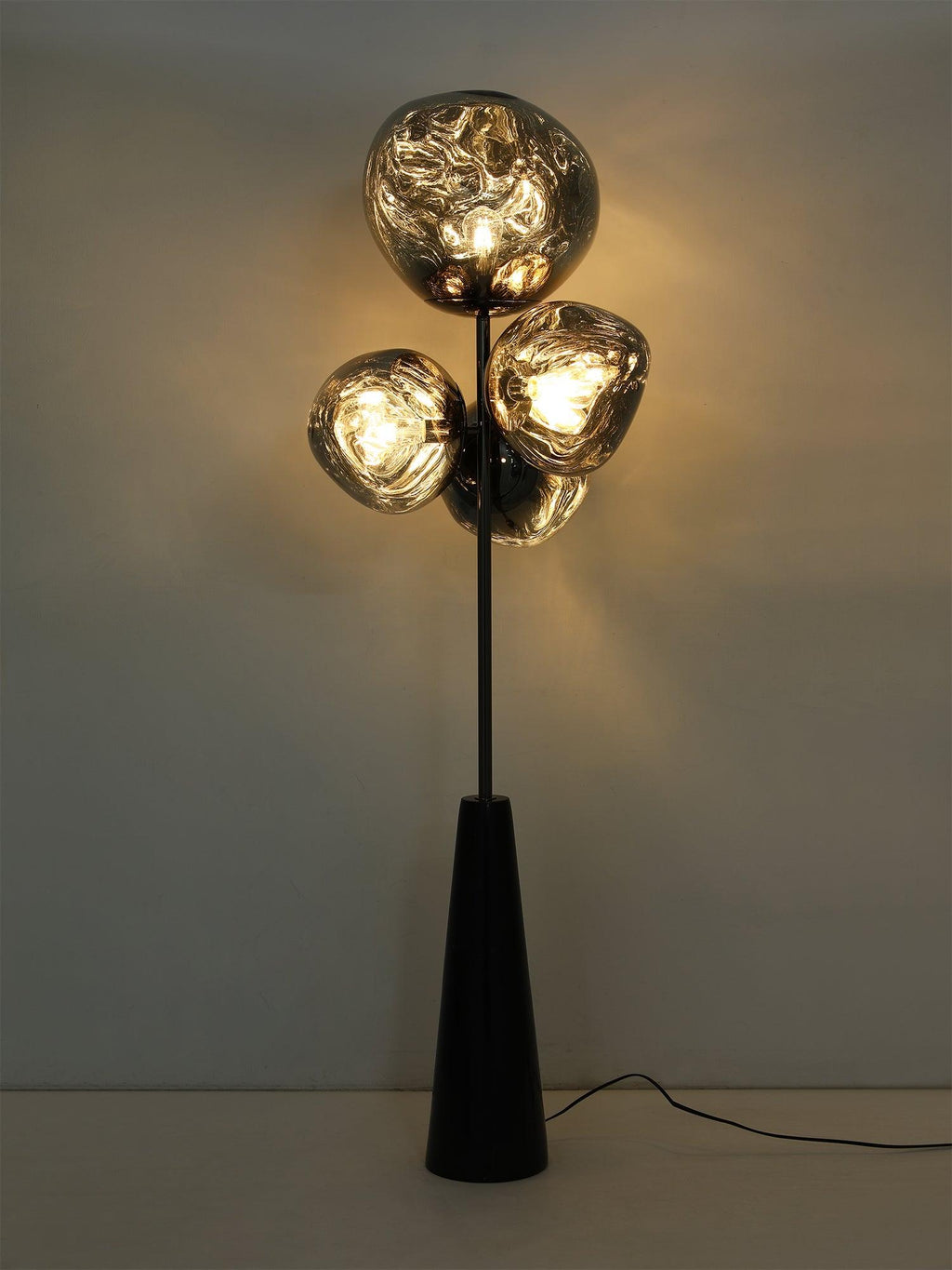 A dramatic, warm-toned studio shot of this Clérachic floor lamp fully lit, its smoke-glass globes glowing against a dark background.