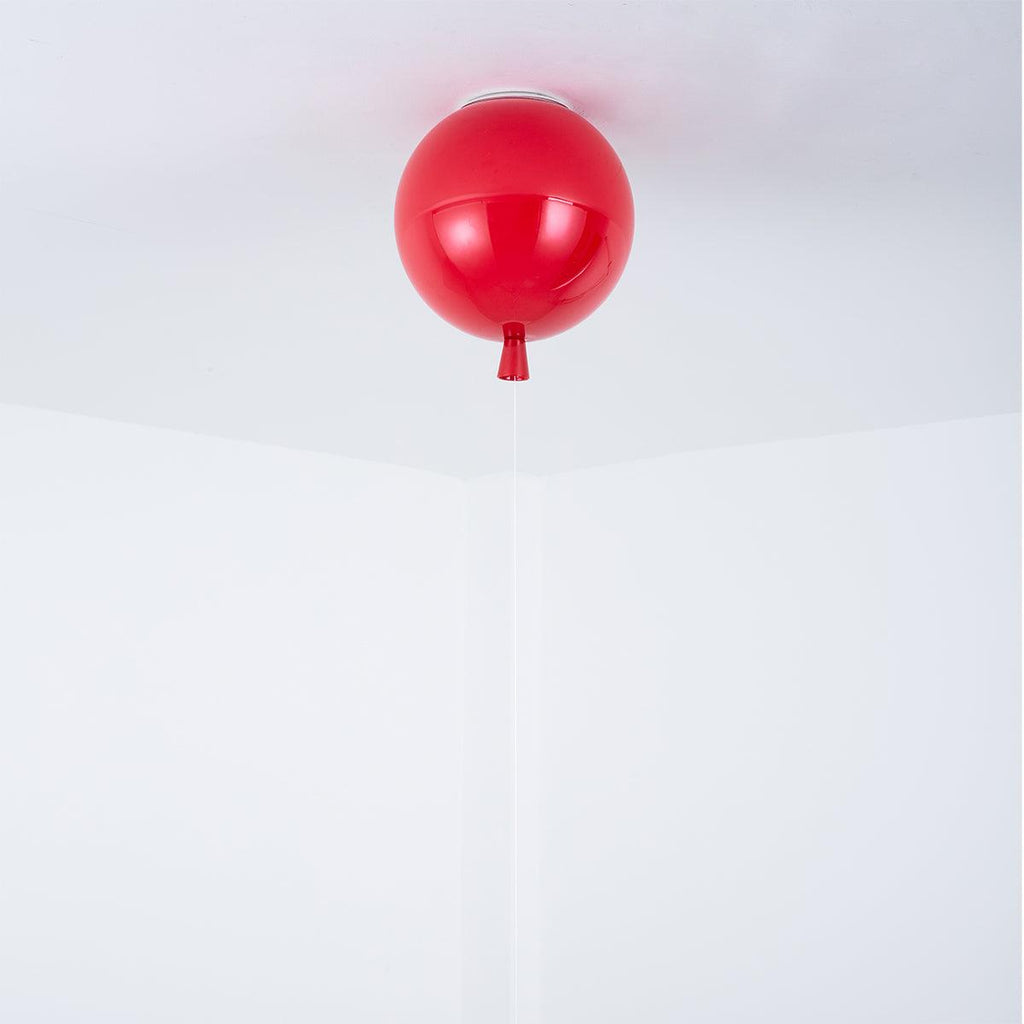 A single red Clérachic balloon light hangs close against a plain white ceiling-wall corner.