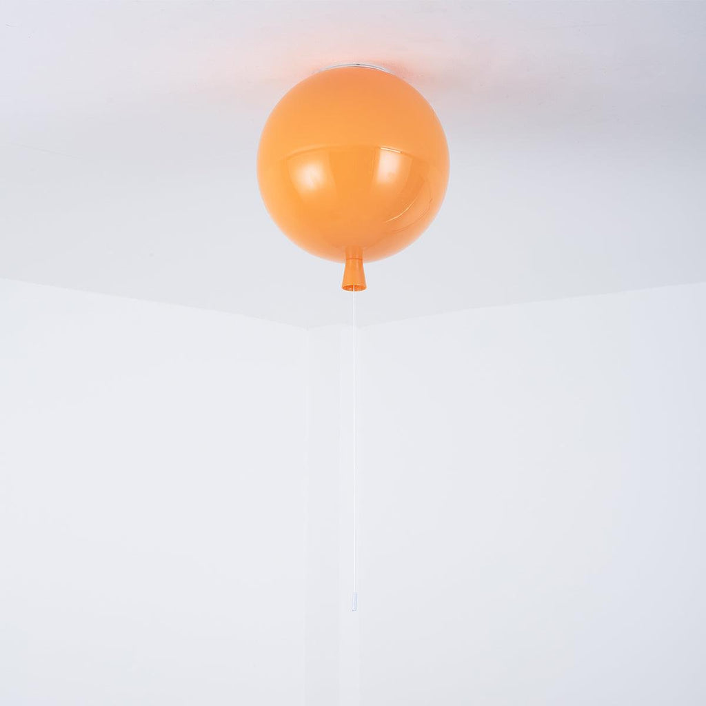 A single orange Clérachic balloon light hangs close against a plain white ceiling-wall corner.