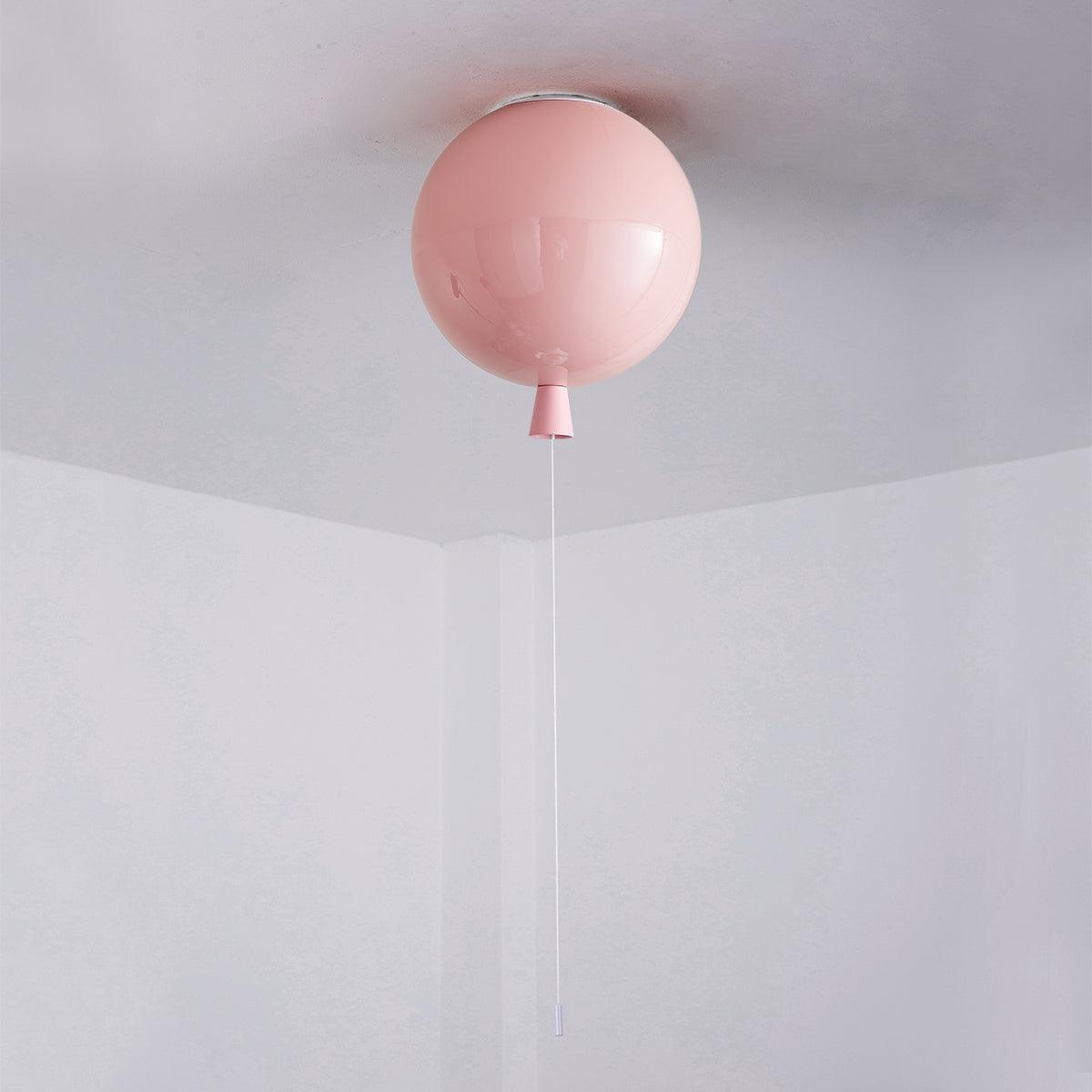 A single pink Clérachic balloon light hangs from a plain white ceiling corner, its pull cord reaching down.