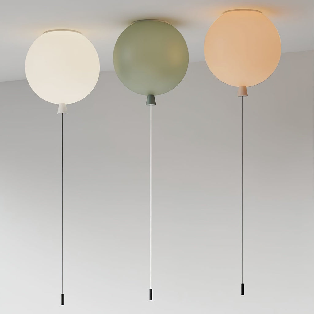 Three Clérachic balloon lights in muted cream, sage and peach tones hang together against a plain grey backdrop.