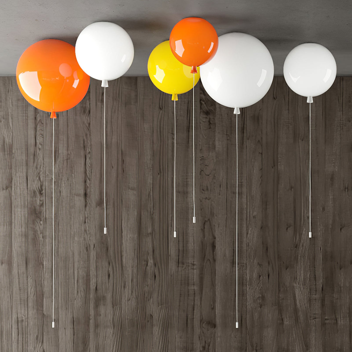 Five Clérachic balloon lights in orange, white and yellow hang against a dark wood-panelled wall, pull cords visible.