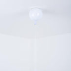 A single white Clérachic balloon light hangs from a plain ceiling corner, its thin pull cord barely visible.
