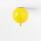 A single yellow balloon-shaped ceiling light from Clérachic hangs against a plain white ceiling, its pull cord dangling below.