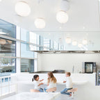 Several plain round globe pendants hang above a kitchen counter where children sit, a different design from this Clérachic balloon light.
