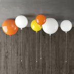 Five balloon ceiling lights in orange, white and yellow from Clérachic mount together on a dark wood-panelled ceiling.