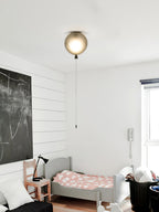 A single grey-toned globe light with a pull cord is mounted near the ceiling of a child's room with a chalkboard wall, from the Clérachic balloon range.