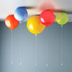 Five balloon ceiling lights in orange, blue, yellow, red and green hang together against a blue-grey ceiling, from Clérachic.