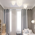 Three white Clérachic balloon lights line a scalloped ceiling edge above striped curtains and a single bed.