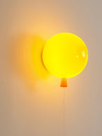 Playful balloon wall sconce with rounded coloured shade lit
