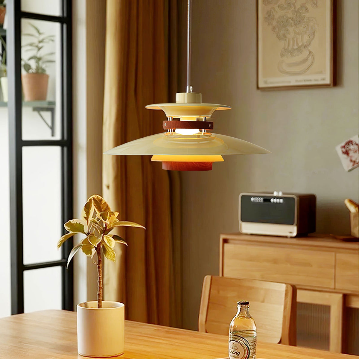 A beige Clérachic pendant light with walnut rings hangs low above a wooden dining table.