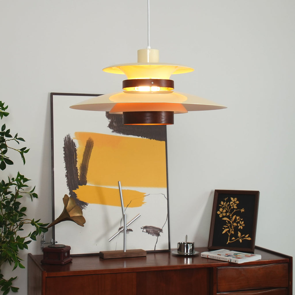 Close view of the walnut ring dividing the tiered metal shades on this lit Clérachic pendant.