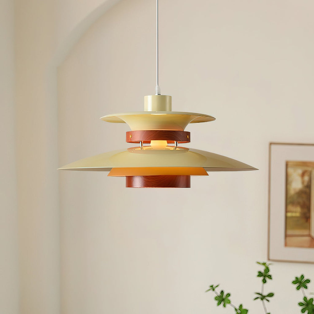 A beige Clérachic pendant hangs in a bright corner with framed art and a trailing plant.
