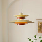 A beige Clérachic pendant hangs in a bright corner with framed art and a trailing plant.