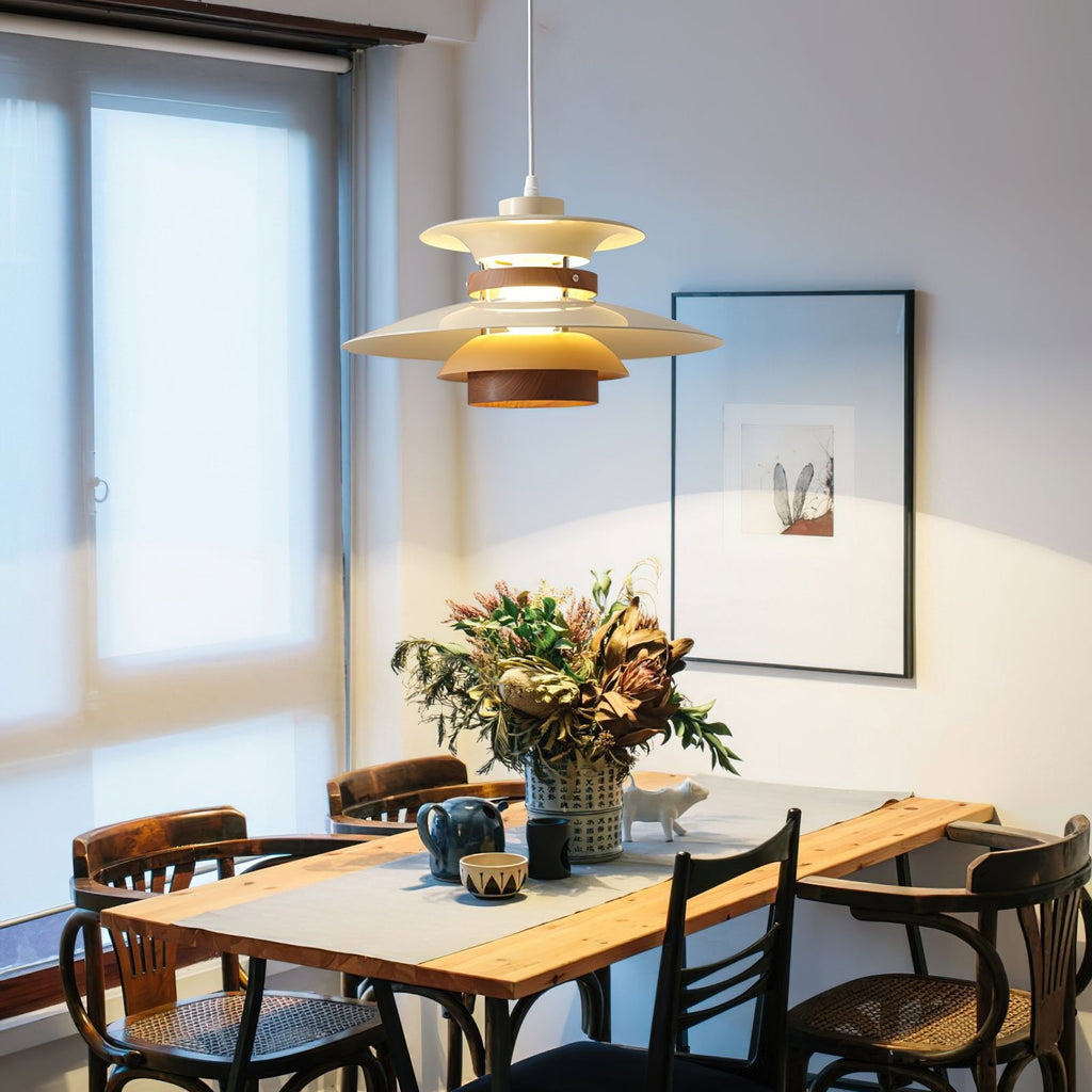 A beige Clérachic pendant hangs over a long dining table set with flowers by a window.