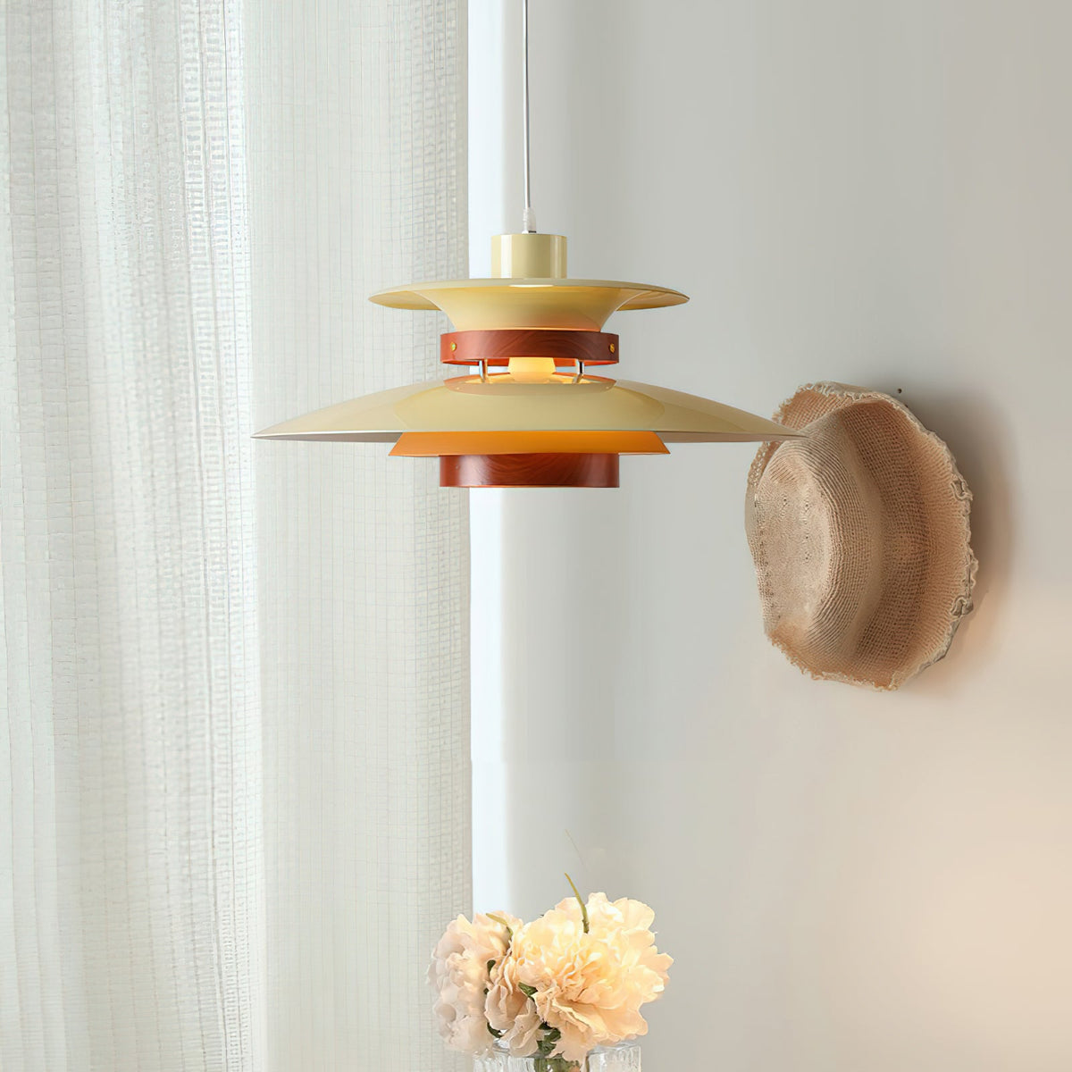 Close view of the beige tiered shades on this Clérachic pendant against a sheer curtain.