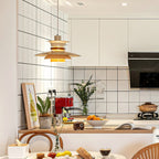 A beige Clérachic pendant hangs in a white tiled kitchen with fresh herbs on the counter.