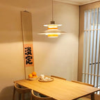 A white Clérachic pendant lights a wooden table in a room with a paper screen door.