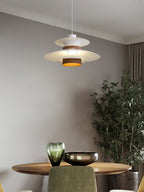 A white Clérachic pendant hangs over a round wooden table with glassware and a plant.