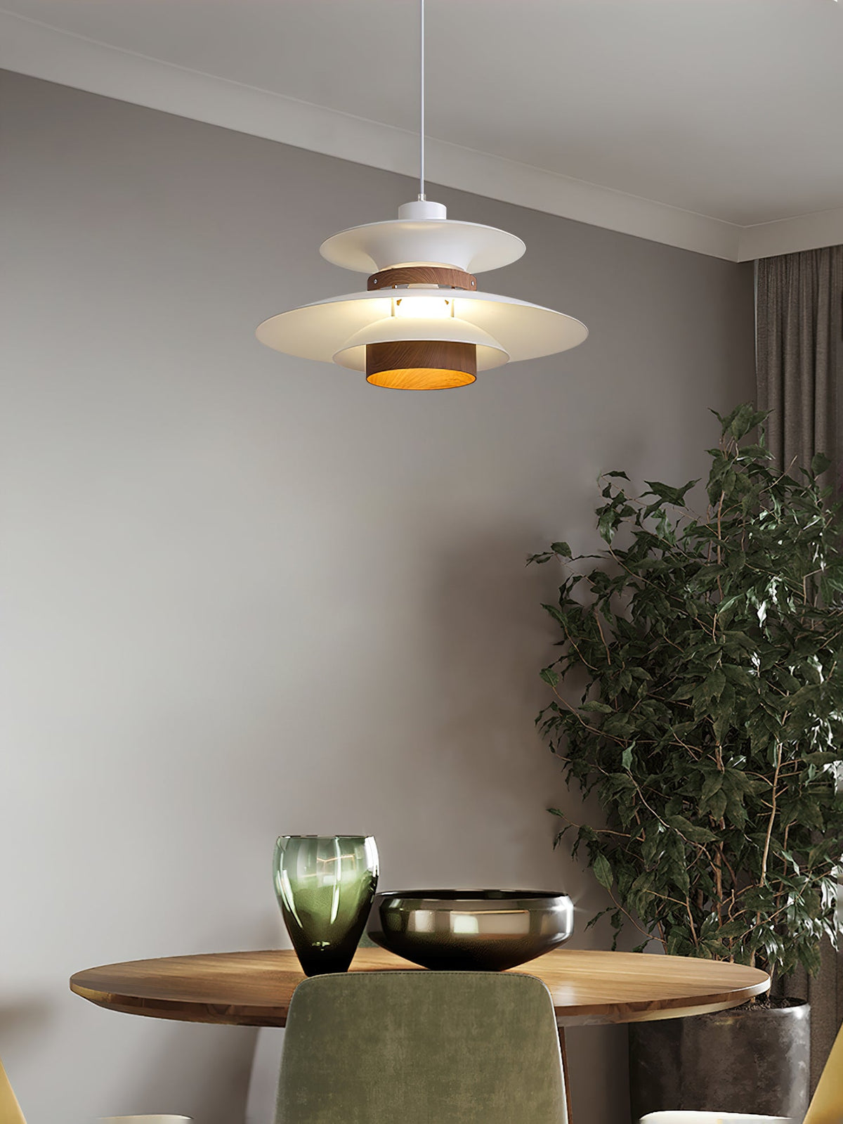 A white Clérachic pendant hangs over a round wooden table with glassware and a plant.