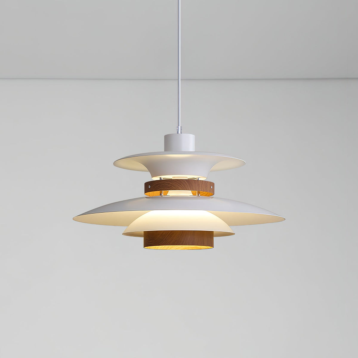 A lit white Clérachic pendant glows warmly against a plain grey wall and ceiling.