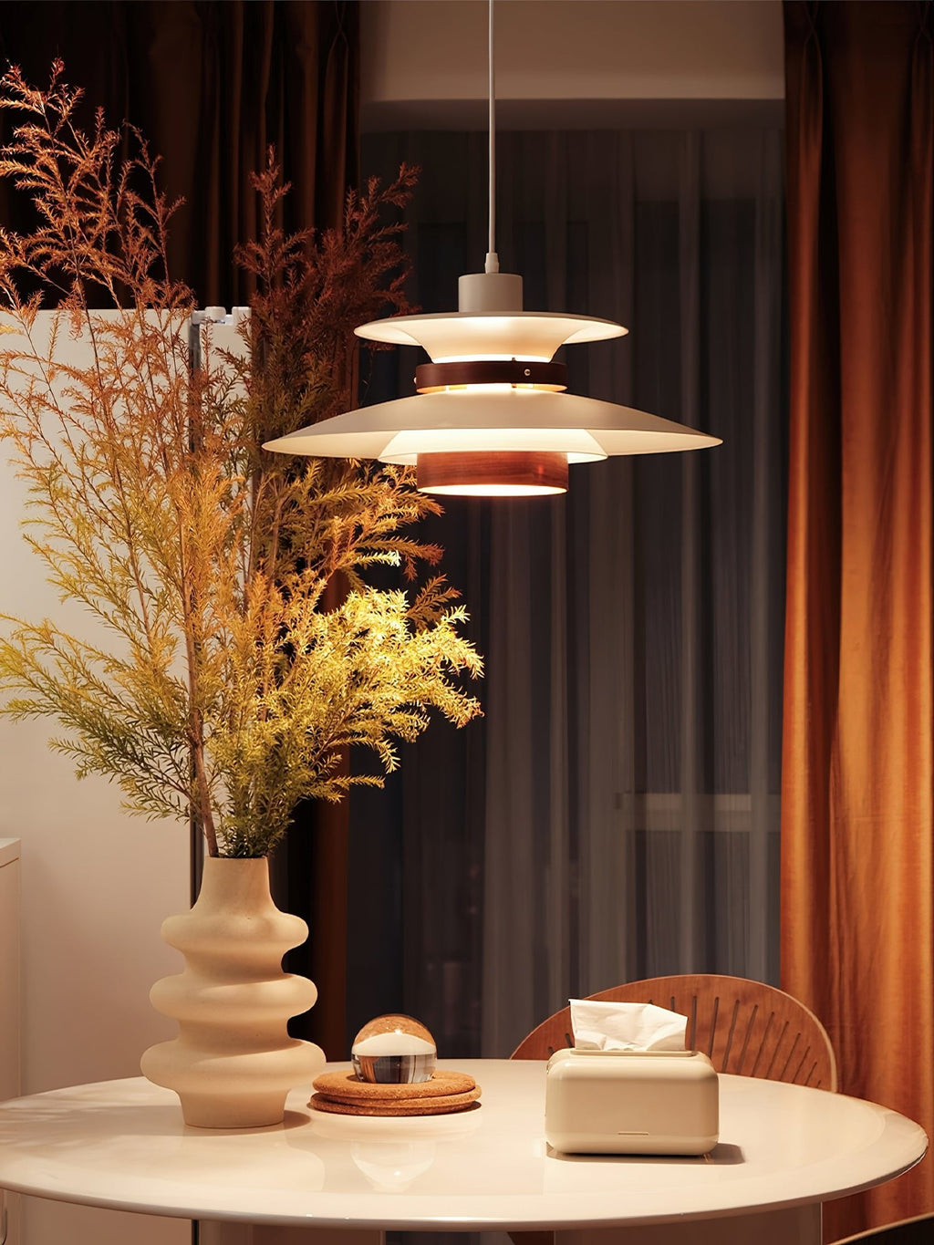 A white Clérachic pendant hangs near a sheer curtain above a round table with dried branches.