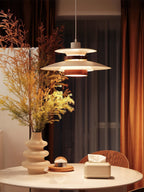 A white Clérachic pendant hangs near a sheer curtain above a round table with dried branches.