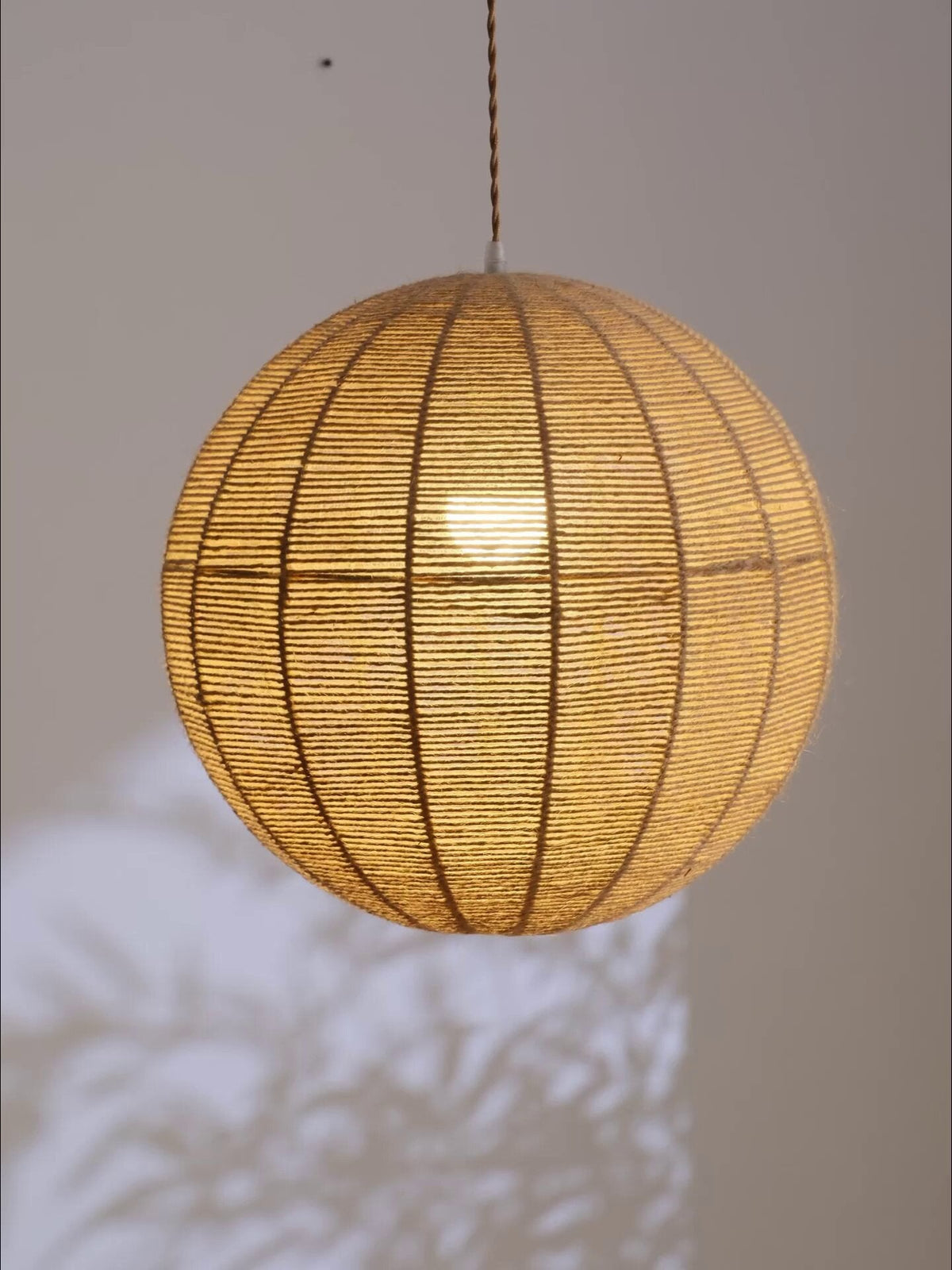 Close view of the hemp rope wound over this Clérachic pendant's spherical frame, its crossing bands catching the light.